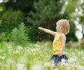 Baby on dandelions field pointing on copy space