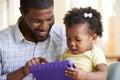 Baby Daughter And Father Playing With Toy On Sofa In Lounge At Home Royalty Free Stock Photo