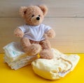 Baby diaper choice concept. Teddy sitting on cloth reusable nappy and disposable diapers