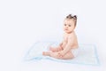 Baby in diapers sitting on a disposable diaper on a white insulated background, space for text, baby hygiene