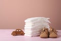 Baby diapers, toy car and child`s shoes on wooden table against pink background Royalty Free Stock Photo