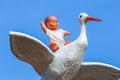 Baby doll sitting on back of stork with blue sky Royalty Free Stock Photo
