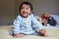 Baby, down syndrome and special needs child happy with a smile sitting on a bed to relax, be curious and playful in Royalty Free Stock Photo