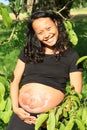 Baby drawn on belly of smiling pregnant woman among leaves