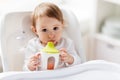 Baby drinking from spout cup in highchair at home Royalty Free Stock Photo