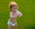 Baby drinking water. Funny blonde child baby drinking fresh and pure water from bottle with a blurred green grass