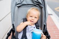 Baby drinking water from special cup sitting in stroller outdoors Royalty Free Stock Photo