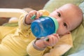 The baby drinks water from a bottle