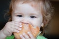 Baby eating bun bread. Close up face. Cute toddler child eating sandwich, self feeding concept. Royalty Free Stock Photo
