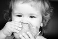 Baby eating bun bread. Close up face. Cute toddler child eating sandwich, self feeding concept. Royalty Free Stock Photo