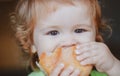 Baby eating bun bread. Close up face. Cute toddler child eating sandwich, self feeding concept. Royalty Free Stock Photo