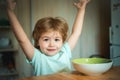 Baby eating food on kitchen. Kid boy eating healthy food at home. Young kid sitting on the table eating with funny Royalty Free Stock Photo