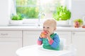 Baby boy eating apple in white kitchen at home Royalty Free Stock Photo