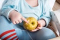 Baby eating fruit. Little boy biting apple sitting in white high chair in sunny kitchen with window and sink. Healthy nutrition Royalty Free Stock Photo