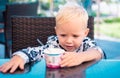 Baby eating kids food. Little boy eating yogurt, have a breakfast in outdoor.