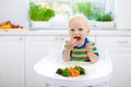 Baby eating vegetables in kitchen. Healthy food. Royalty Free Stock Photo