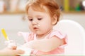 A baby eating yogurt with some on her face. Royalty Free Stock Photo