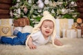 Baby in elf costume playing with old wooden train and soft toy bears under the Christmas tree, vintage. Royalty Free Stock Photo