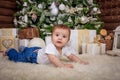 Baby in elf costume playing with old wooden train and soft toy bears under the Christmas tree, vintage. Royalty Free Stock Photo