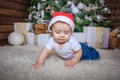 Baby in elf costume playing with old wooden train and soft toy bears under the Christmas tree, vintage. Royalty Free Stock Photo