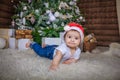 Baby in elf costume playing with old wooden train and soft toy bears under the Christmas tree, vintage. Royalty Free Stock Photo