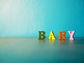 Baby. English alphabet made of wooden letter color. Alphabet baby on wooden table and background is powder blue