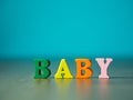 Baby. English alphabet made of wooden letter color. Alphabet baby on wooden table and background is powder blue