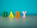 Baby. English alphabet made of wooden letter color. Alphabet baby on wooden table and background is powder blue