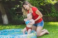 Baby enjoying swimming in the pool at garden with young mother Royalty Free Stock Photo