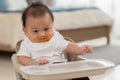 Baby face dirty after feeding pumpkin mashed enjoy and amazed.Adorable smudgy asian baby learning to eating and feeding vegetable