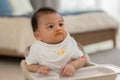 Baby face dirty after feeding pumpkin mashed enjoy and amazed.Adorable smudgy asian baby learning to eating and feeding vegetable