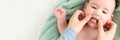 Baby face massage banner with copy space. Mother gently stroking baby boy face with both hands. Close up. Baby smiling. Royalty Free Stock Photo