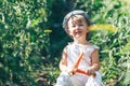 Baby farmer with carrots and cacual clother sitting in green grass