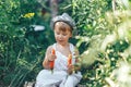 Baby farmer with carrots and cacual clother sitting in green grass