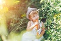 Baby farmer with carrots and cacual clother sitting in green grass