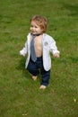 Baby fashion. Funny little business man in suit, jacket and necktie. Cute little baby on the meadow field. Toddler child Royalty Free Stock Photo