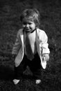 Baby fashion. Funny little business man in suit, jacket and necktie. Portrait of a little baby boy playing outdoor in