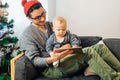 Baby with father sitting and using digital tablet during Christmas
