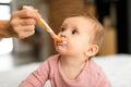 Baby feeding. Cute little infant girl eating from spoon, caring mother giving healthy food to her hungry toddler child Royalty Free Stock Photo