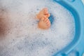 Baby feet in a blue bubble bath. Baby detergent, hygiene. Baby skin care. Background, texture of soap bubbles Royalty Free Stock Photo