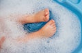 Baby feet in a blue bubble bath. Baby detergent, hygiene. Baby skin care. Background, texture of soap bubbles Royalty Free Stock Photo