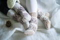 Baby feet in knitted wool socks on a white blanket next to a fir cone Royalty Free Stock Photo