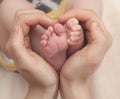 Baby feet in mother hands. Feet on female heart shaped hands closeup. Happy family concept. Mom and her child. Royalty Free Stock Photo