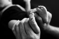 Baby feet in mother hands Mom her Child. Black and white photo, black background Royalty Free Stock Photo