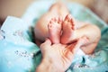 Baby feet with partial view of adult`s hand on blue blanket