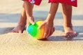 Baby feet walking on sand beach grabbing rugby ball, playful toddler wearing inflatable armbands hand holding ball Royalty Free Stock Photo