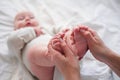 Baby feets in mother hands. Young caucasian woman makes massage for happy infant baby on white bed at home. Babycare Royalty Free Stock Photo