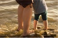 Baby and female feet in the water, the tide. Mom with the baby for both hands walk along the seashore at sunset. Support and mater Royalty Free Stock Photo