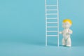 A baby figurine and a ladder on a light blue background. The concept of development and growth