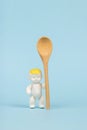 A baby figurine with a large wooden spoon on a blue background